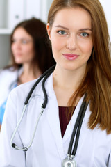 Fototapeta premium Young beautiful female doctor smiling to patient while consulting her.