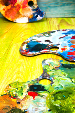 Painting palettes on colorful wooden background