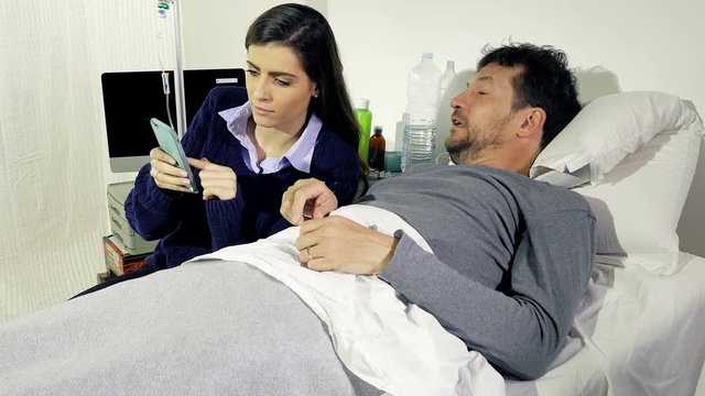 Man in hospital bed laughing looking pictures on the phone with girlfriend