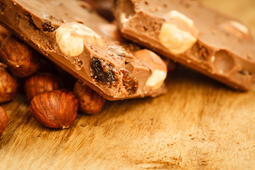 Milk chocolate and hazelnuts on wooden table