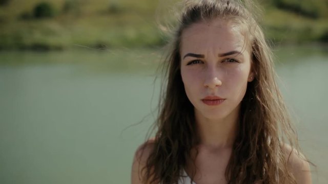 Young woman looking at camera on lake and grimacing