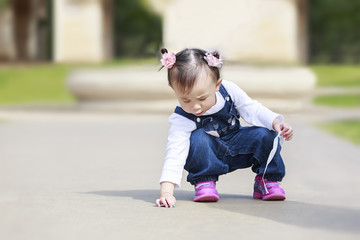 Asian toddler girl gathering things on the ground