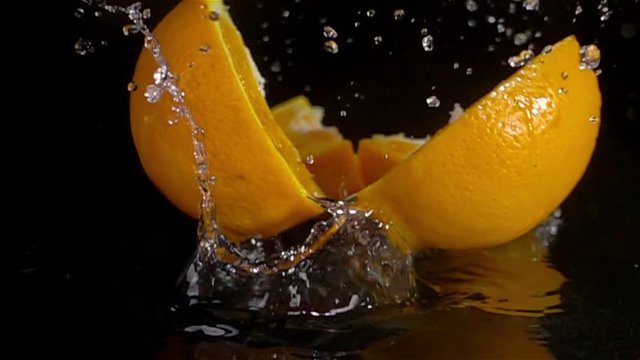 fruit splashing,orange falling on water breaking in slices slow motion