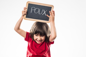 furious young child holding a school slate against head lice