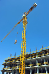 Crane lifting concrete mixer container against blue sky