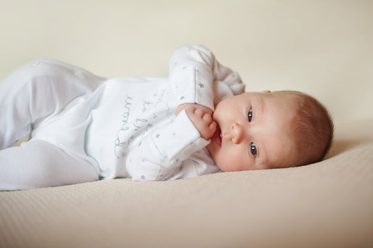 child is lying on bright plaid in white pajamas