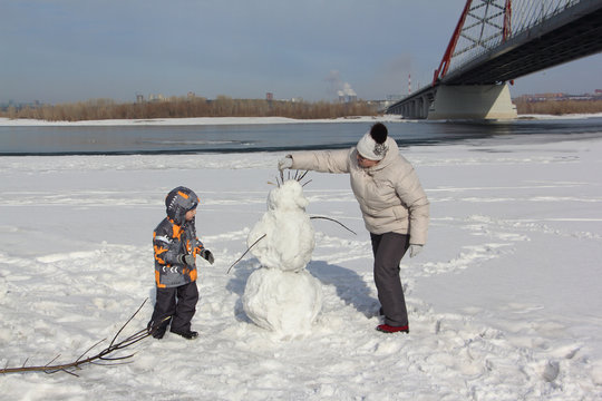 The Woman In A Light Jacket And The Little Boy Building A Snowman
