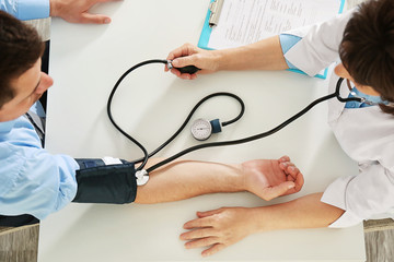 Female doctor measuring man blood pressure with tonometer