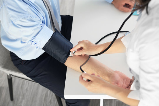 Female doctor measuring man blood pressure with tonometer