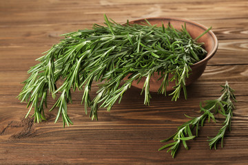 Fresh rosemary in bowl on wooden table
