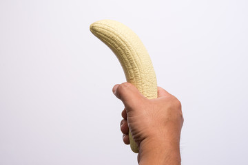 man's hand holding a banana like a big penis that symbolizes erection and potency
