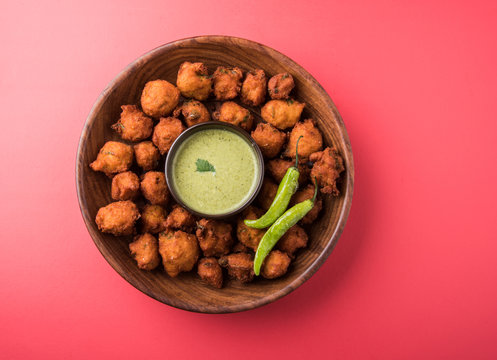 Delicious Tasty and Yummy Indian Moong Dal vada or moong dal pakoda or moong vade or Pakora (Fritter) with fried green chilli, red and green hot sauce.