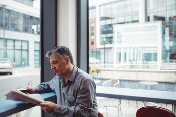 Man reading newspaper and holding coffee cup