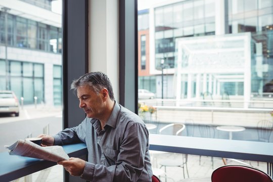 Man reading newspaper and holding coffee cup