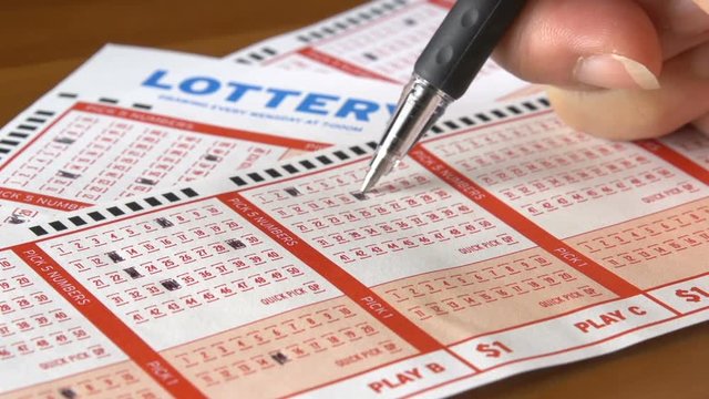 Shot of a pen filling in numbers on a lottery ticket.