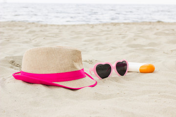 Fototapeta na wymiar Sunglasses, straw hat and sun lotion on sand at beach, sun protection, summer time