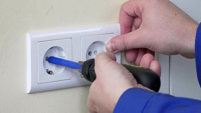hands with screwdriver install outlet on wall