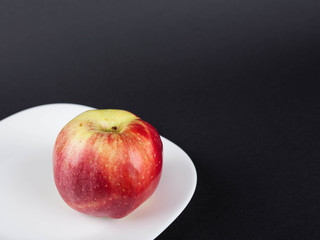 Red single apple on white plate