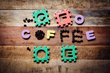 The word coffee made from coffee beans on wooden background.