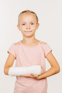 Smiling  girl with broken arm  is standing and looking at the camera