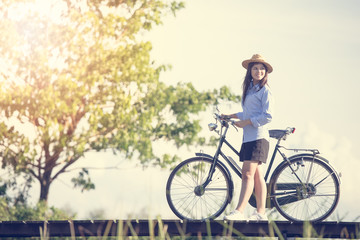 Obraz premium Woman with vintage bike on the bridge. Vintage tone filter.