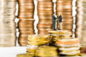 Businessman shake hands business on stack of money coin.