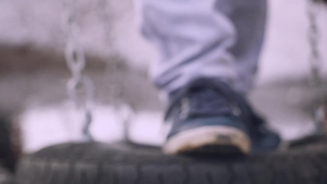 Woman having fun on tire swin on winter copy space outdoors background in slow motion. Close up of legs with shoes trainers. 1920x1080