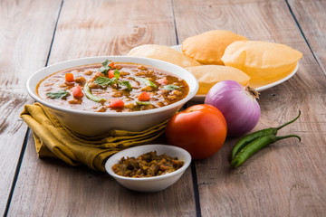 spicy chick peas also known as Chola Masala or Chana Masala or Chole served with fried puri, pickle...