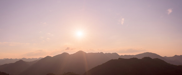 Panorama of sun flare with pink sky and mountains