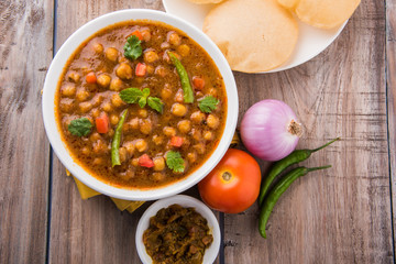 spicy chick peas also known as Chola Masala or Chana Masala or Chole served with fried puri, pickle...