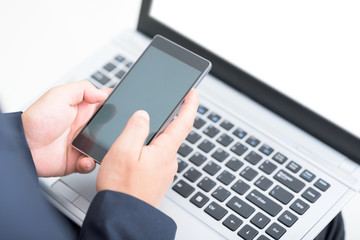 Businessman using smart phone and laptop.