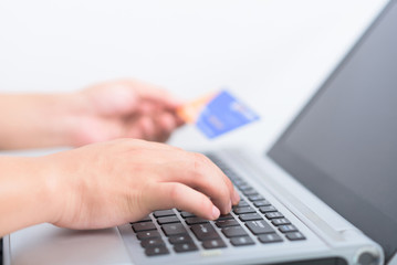 Man using credit card and laptop for online payment.
