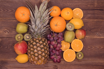 Tasty fruit background with orange, kiwi, grape, apples and lemon on the wooden table