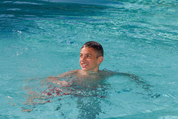 Teen boy dives and swims in the pool