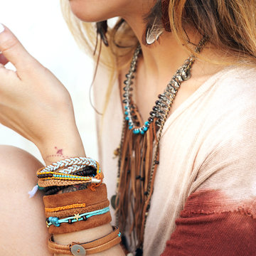 Female neck and hands with many boho bracelets, leather necklace and earrings with feathers