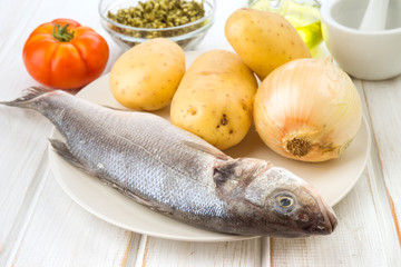whole seabass raw potatoes and onion in tray