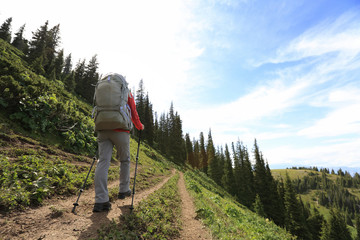 Obraz premium young woman backpacker hiking on beautiful mountain peak trail