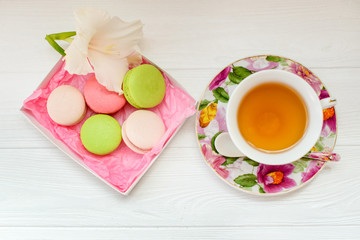 Color macaron and cup of tea on a white wooden background. Flat lay