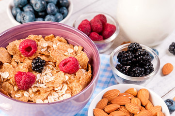 healthy breakfast with cornflakes berries, milk and almond nuts on wooden table