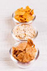 assortment breakfast cereals in small glass dishes on wooden table, almond nuts close-up