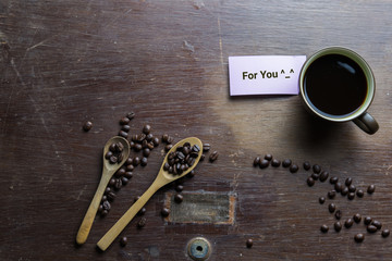 Coffee cup, coffee beans on wooden table with note paper.