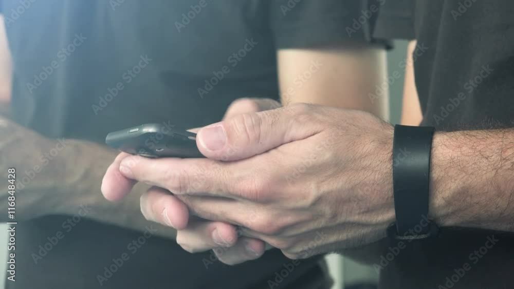 Wall mural casual man using smart phone to send text message, male hands holding mobile telephone device