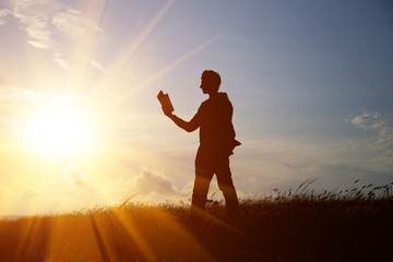 Man reading in the park against sunset