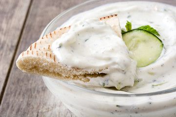 Tzatziki and pita bread on a rustic wooden table

