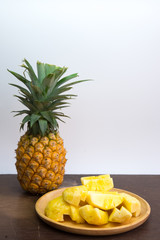 Pineapple fruit cut on wooden plate on white background