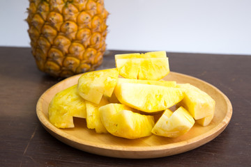 Pineapple fruit cut on wooden plate on white background