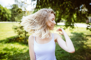 Outdoors portrait of beautiful happy girl with flying hair.Blooming lady's portrait in a s green summer garden