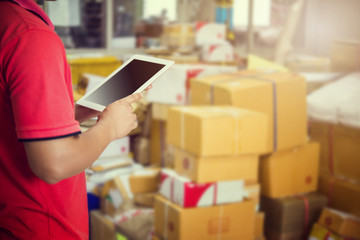 A Man using tablet checking the parcel in warehouse.
