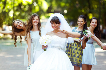 Bride rises the sign of virctory posing with pretty bridesmaids
