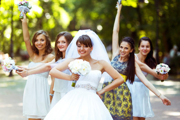 Smiling bride with a bouquet in her arm poses with a girls in pa